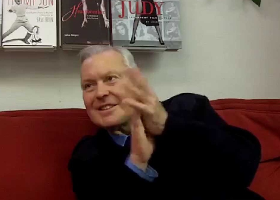 Photograph of John Mitzel on red couch.